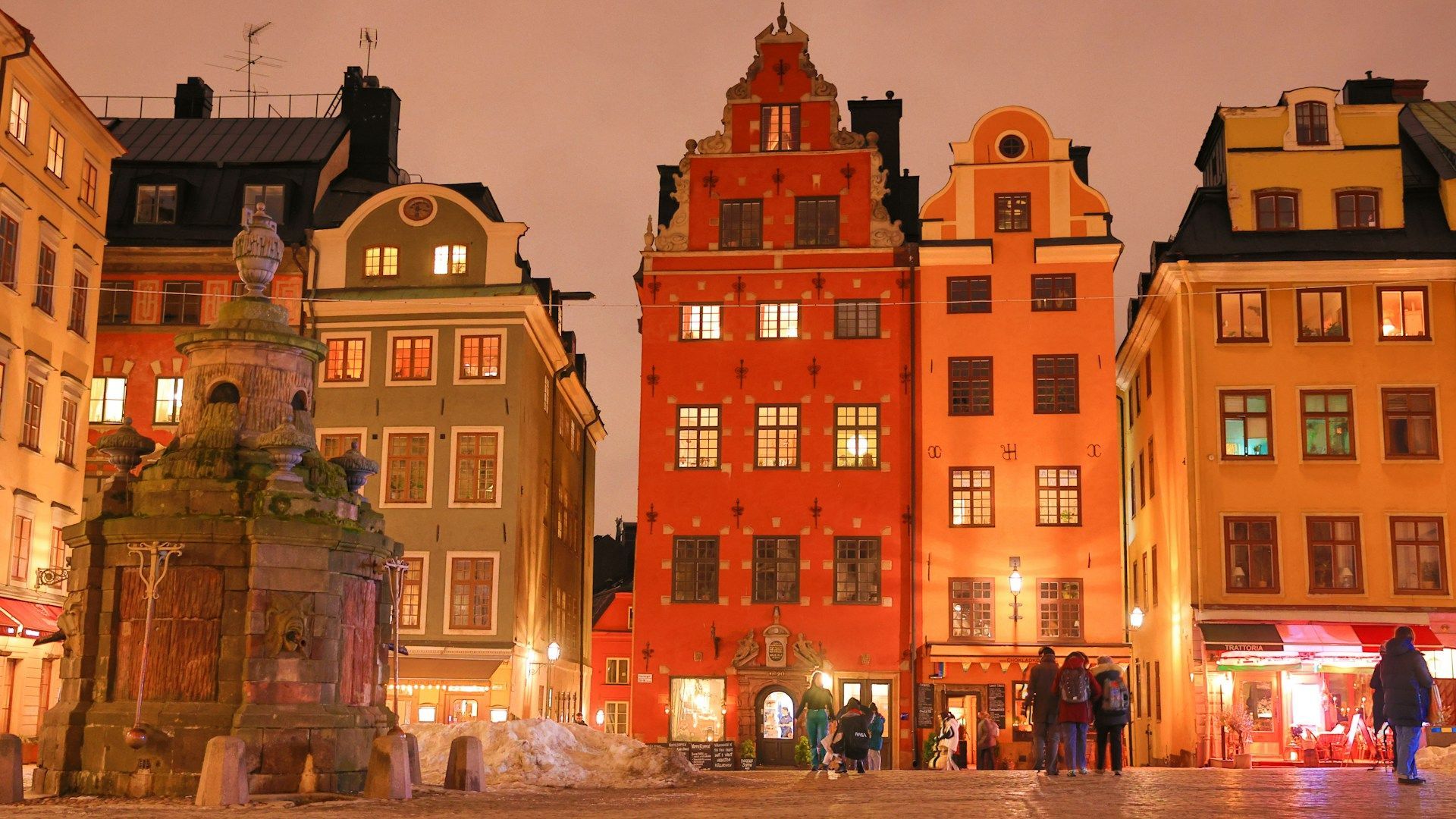 Colorful, historic buildings in Stortorget square, Stockholm, illuminated at dusk with warm lighting.