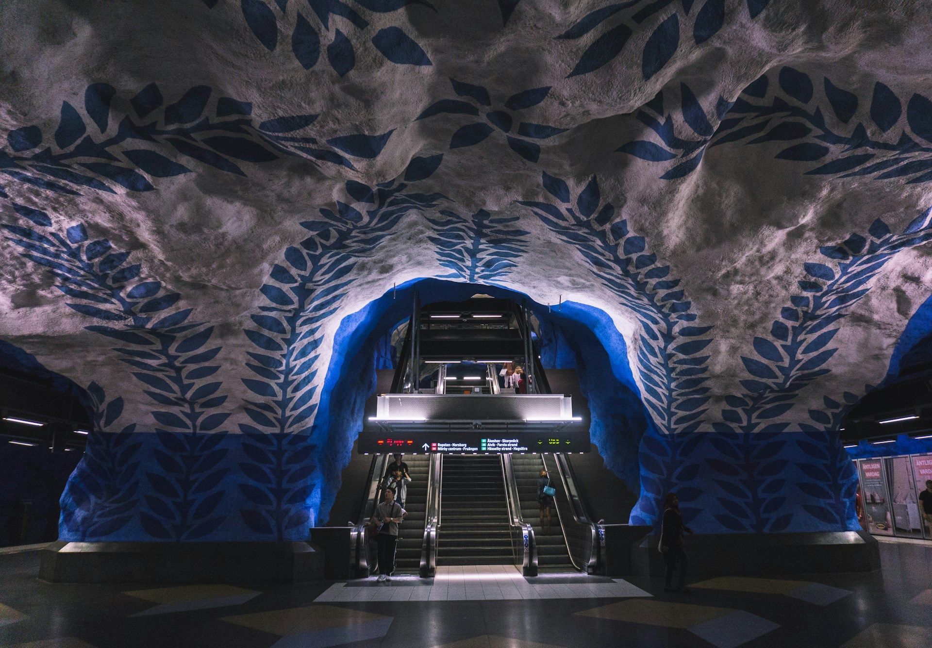 T-centralen subway station in Stockholm with blue, leafy murals painted on the rough, rock ceiling.
