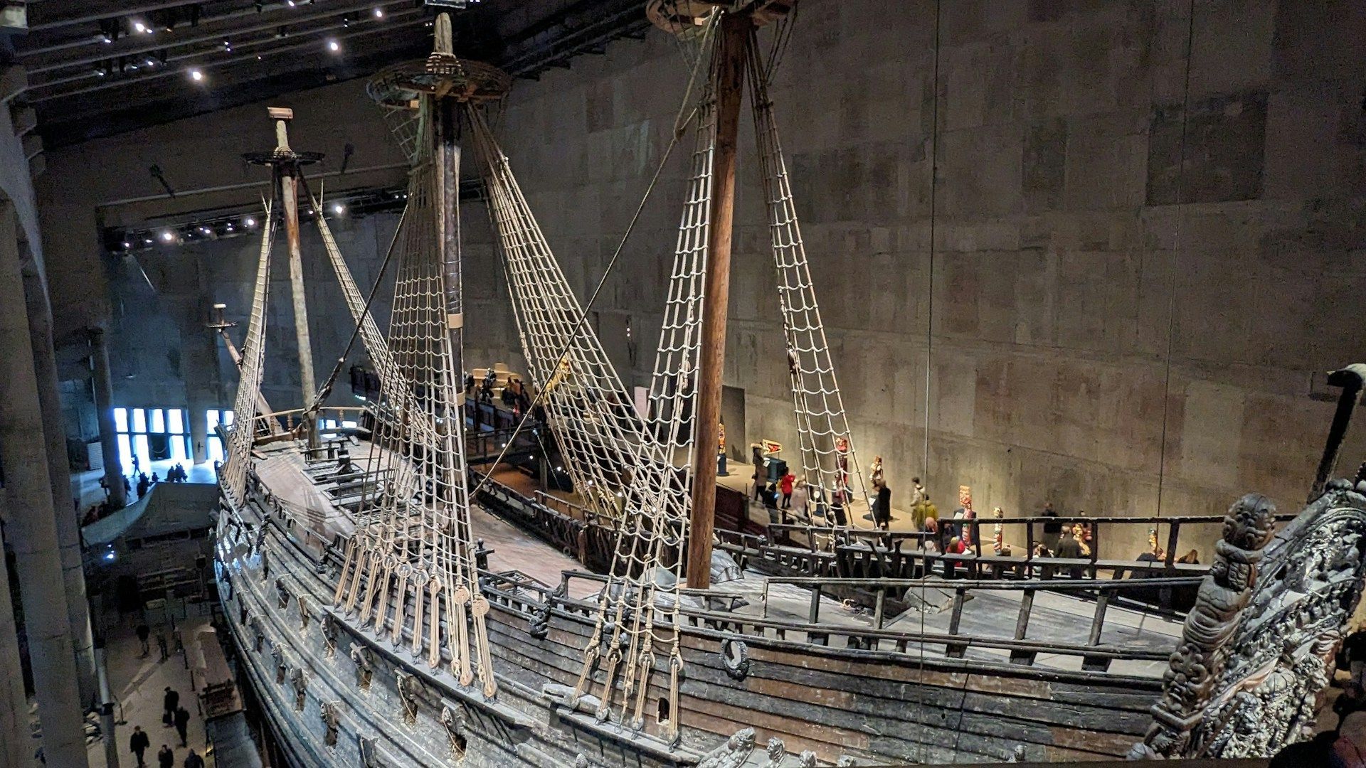 A large, salvaged 17th-century warship, the Vasa, inside a dimly lit museum hall in Stockholm.