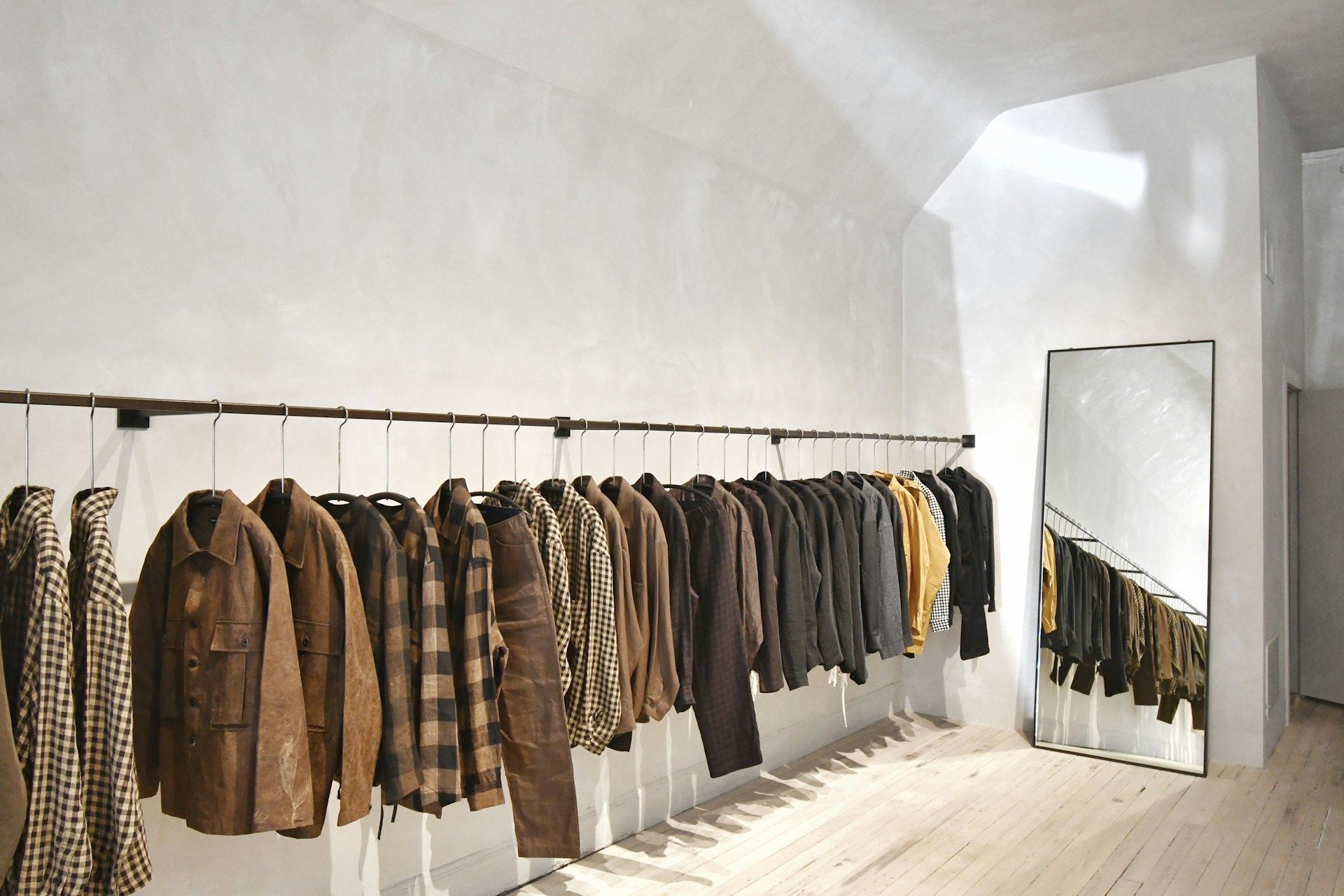 A row of assorted jackets hanging on a rack in a minimalist store in Stockholm.