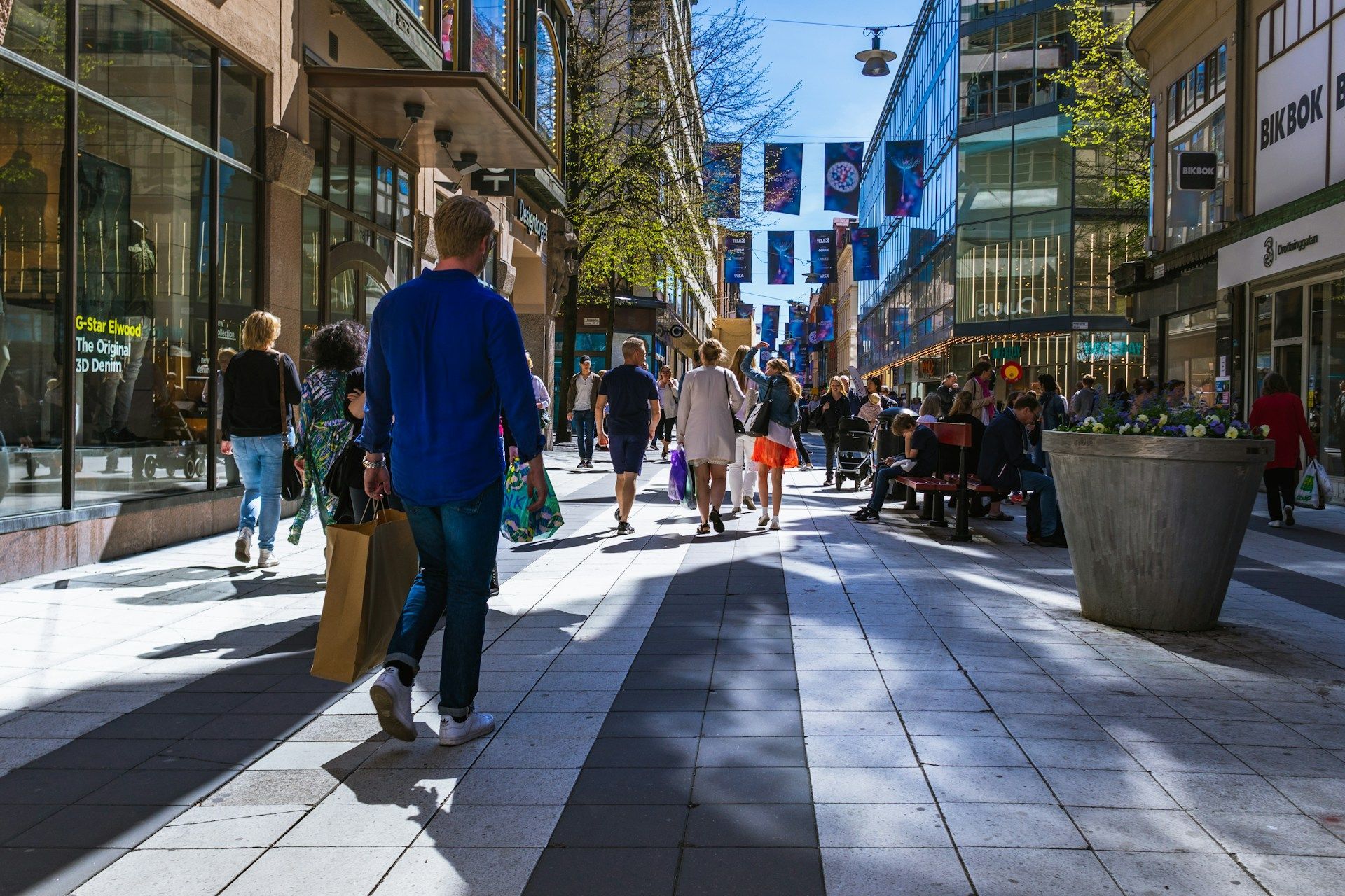 Shoppers walk along Drottninggatan in Stockholm during spring.