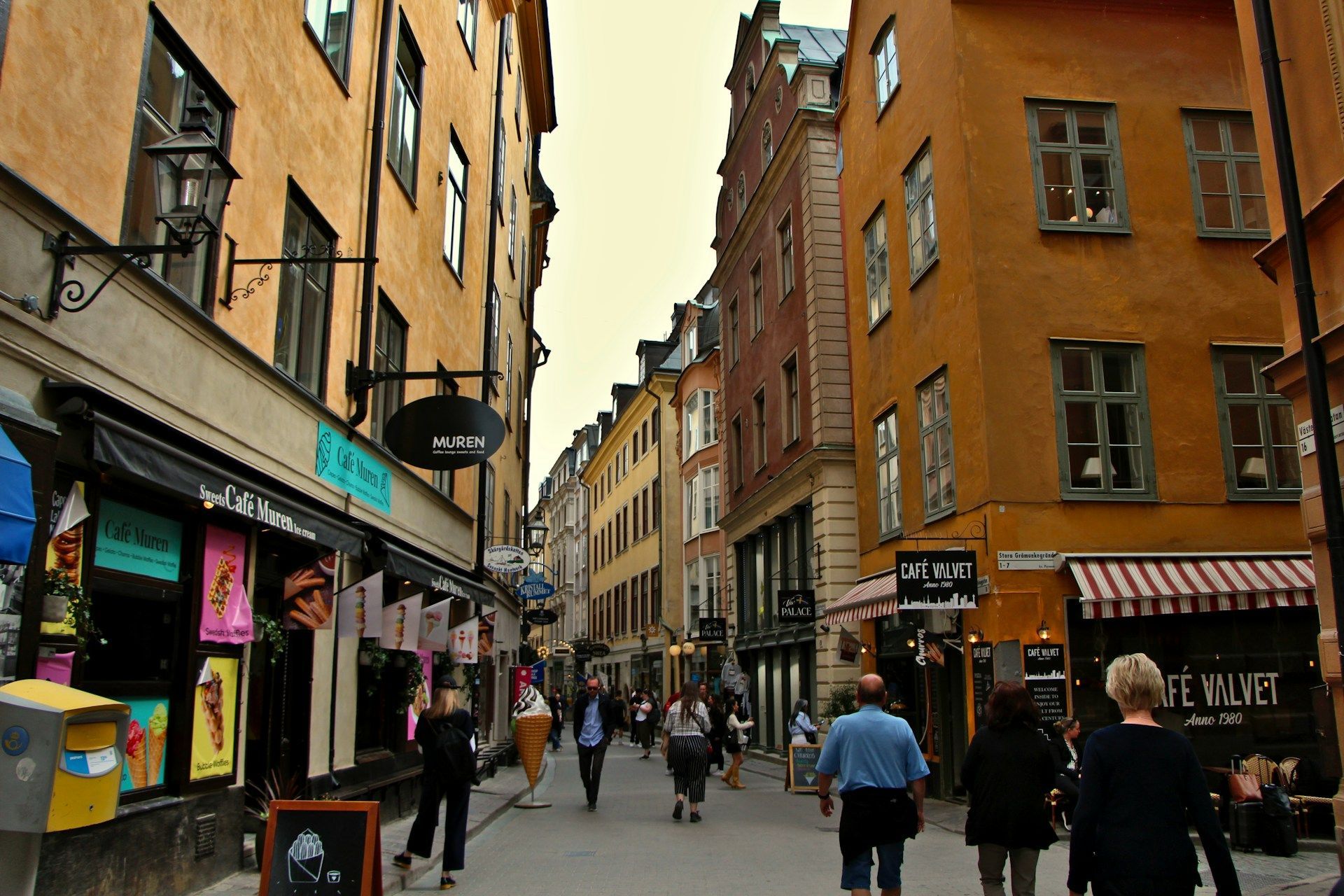 Pedestrians walk down a narrow cobblestone street in Gamla Stan in Stockholm.