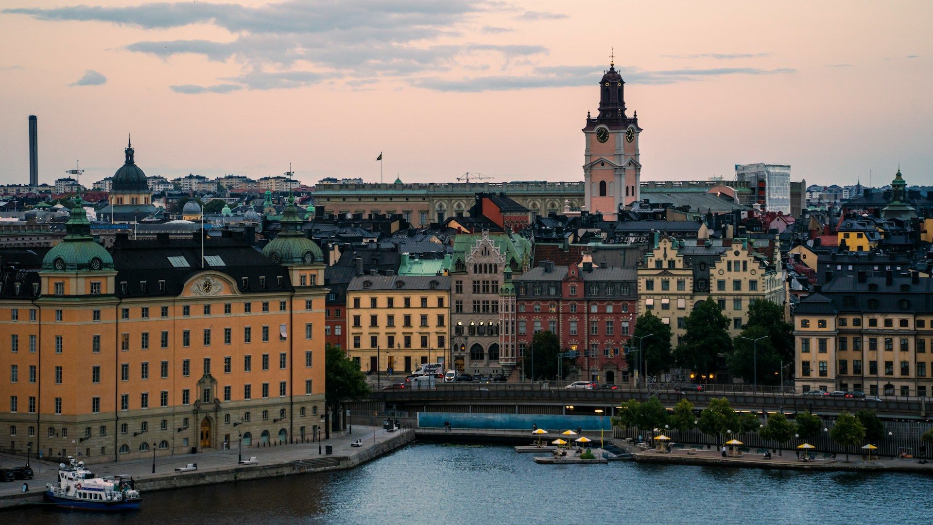 Cityscape of Stockholm at dusk, featuring colorful buildings, water, and a tall clock tower.
