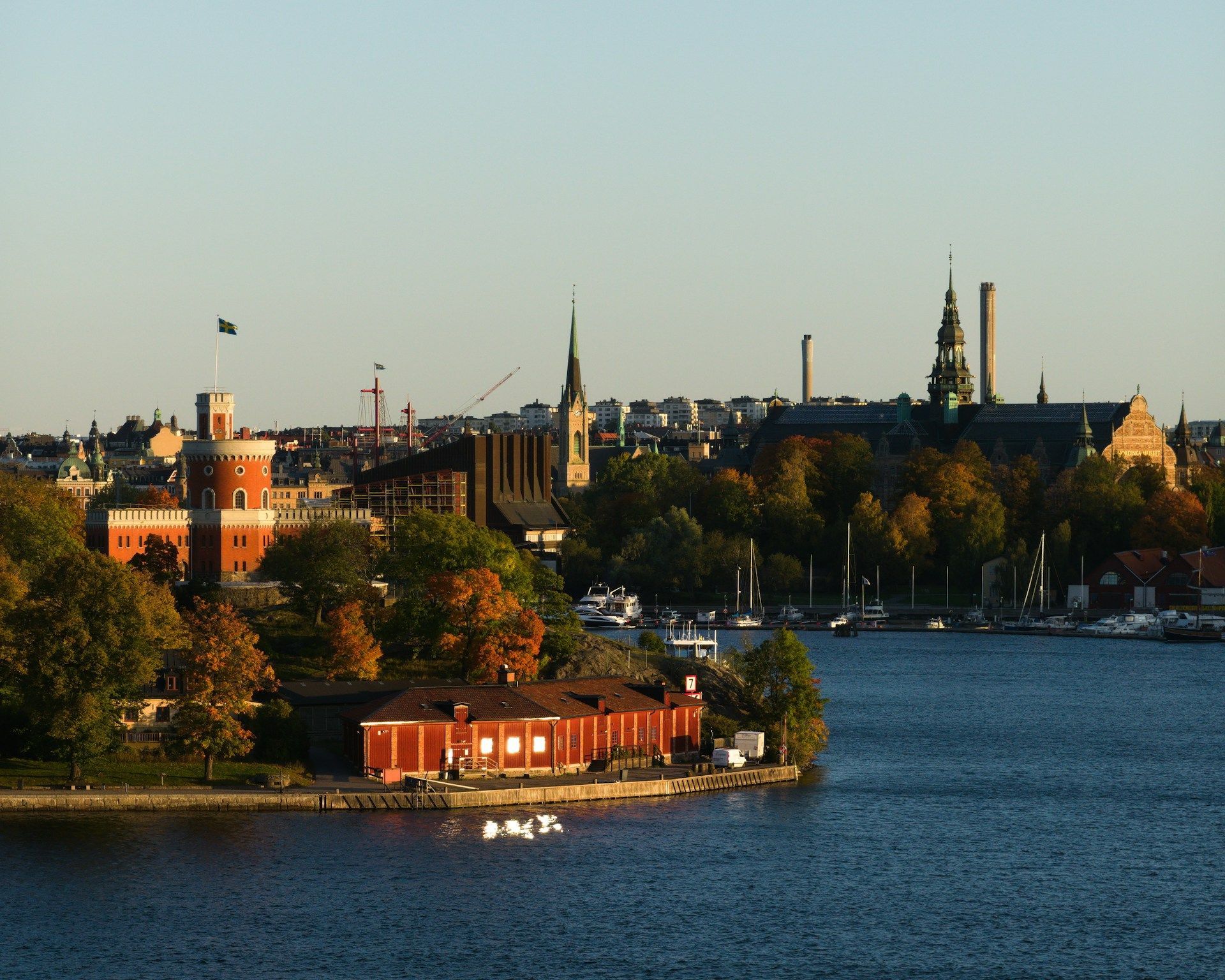 View of Stockholm waterfront with buildings, water, trees, and blue sky.