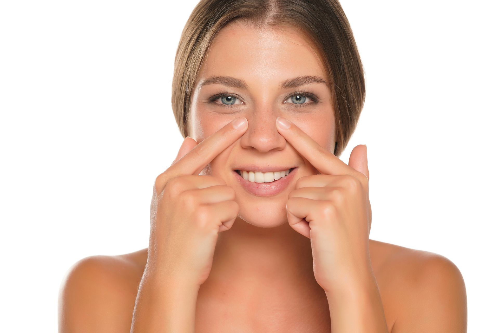 A woman is touching her nose with her fingers and smiling.