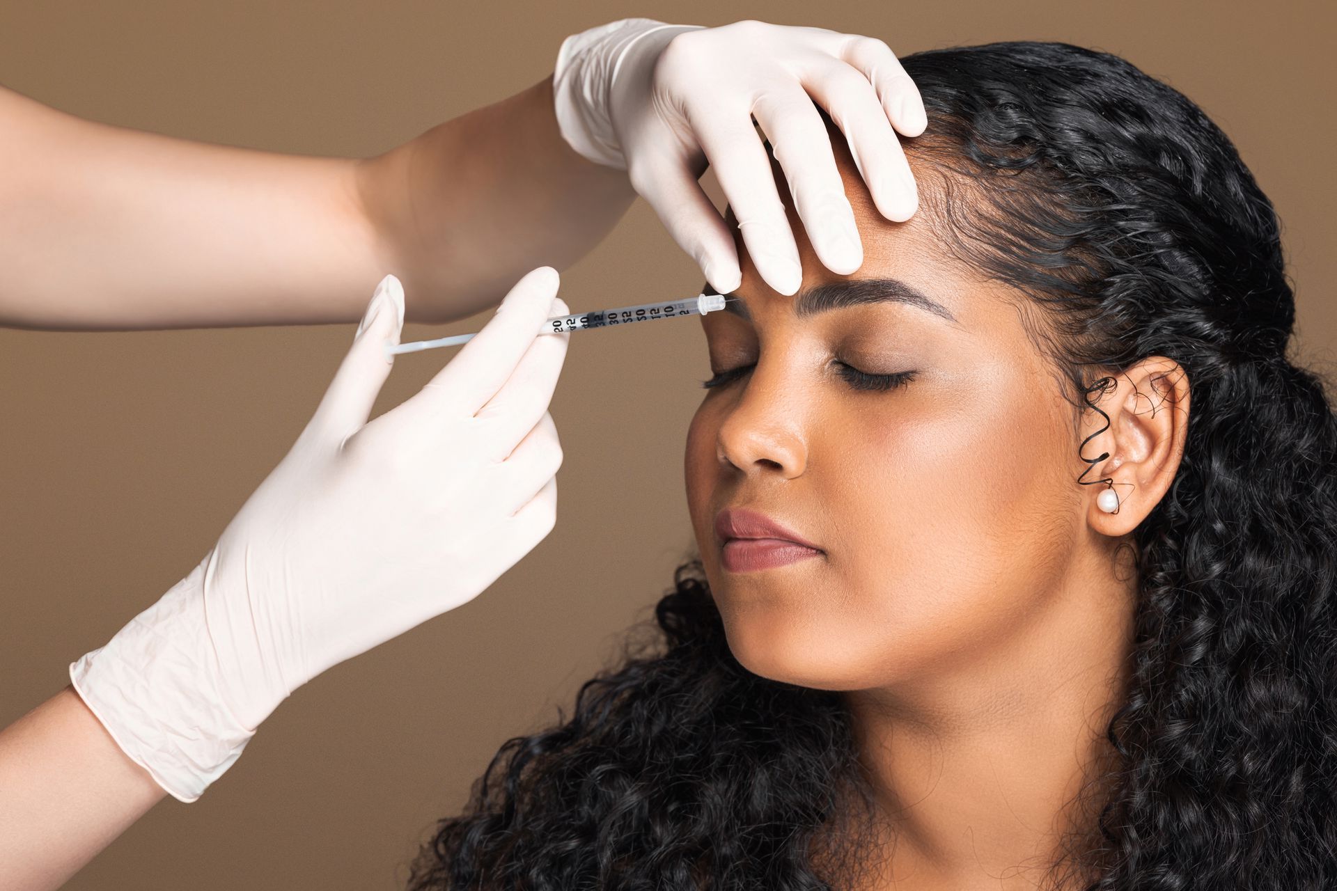 A woman is getting a botox injection in her forehead.