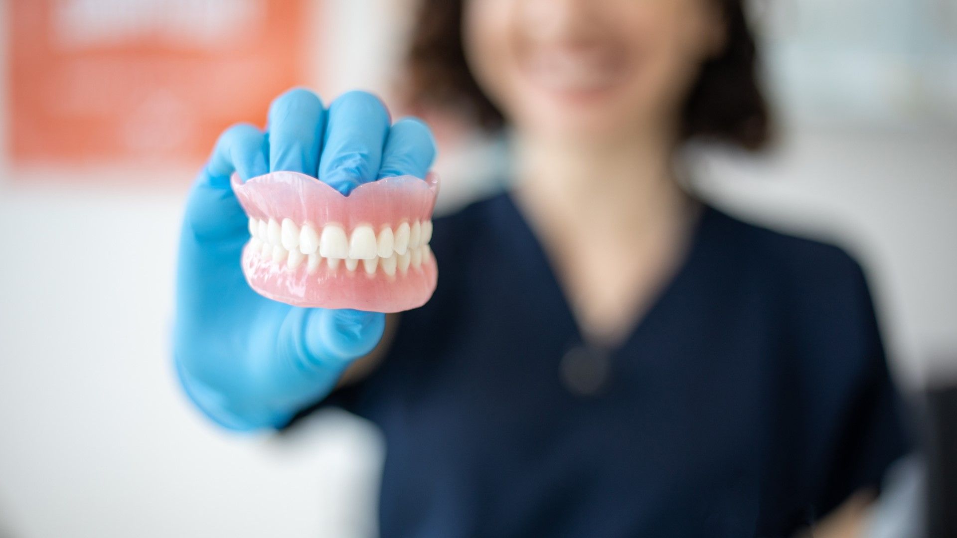 A dentist is holding a pair of dentures in her hand.