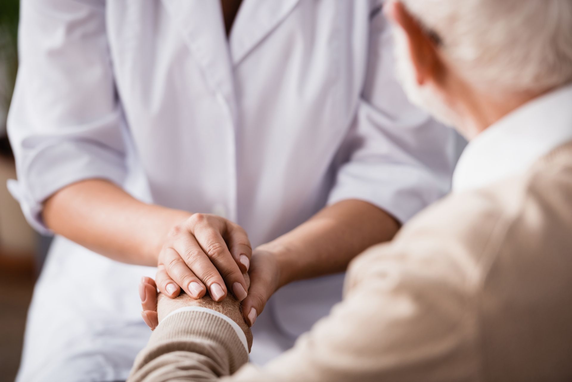 Two people gently holding hands during a calm conversation in a bright setting