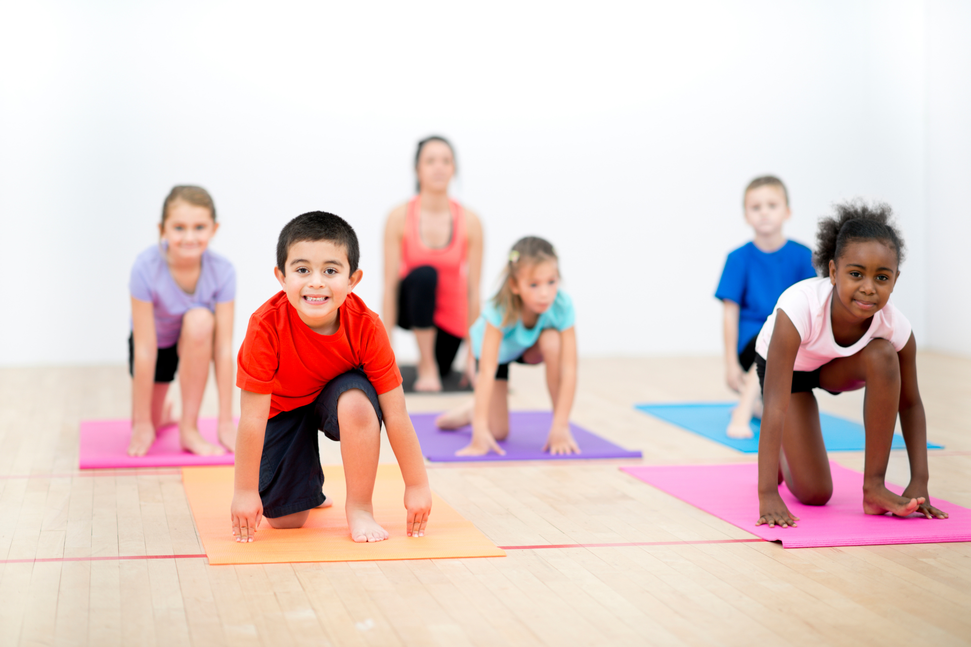 Children doing yoga poses on colorful mats in a bright studio
