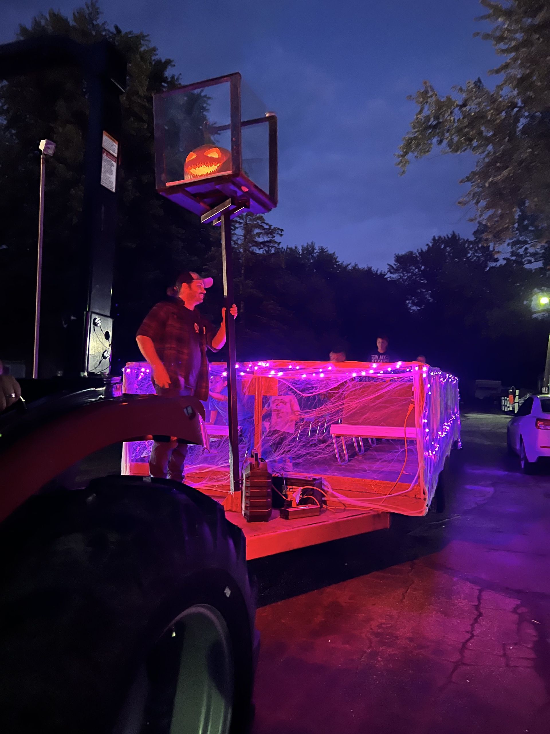 A man is standing in front of a basketball hoop covered in purple lights.