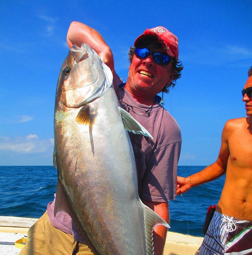 A man is holding a large fish in the ocean