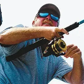 A man wearing sunglasses and a hat is holding a fishing rod.