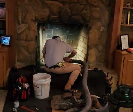 a man is working on a fireplace with a vacuum cleaner .
