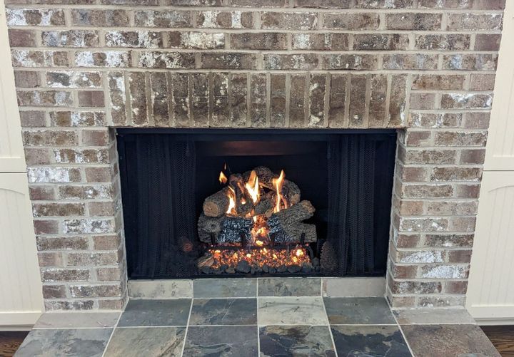 a brick fireplace with a stack of logs in it