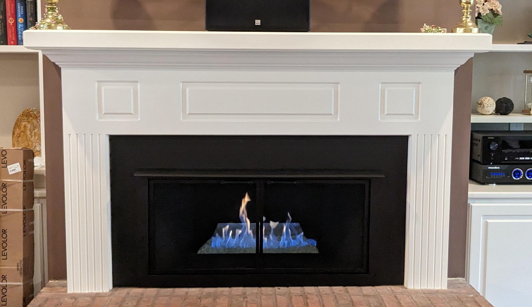 a fireplace with a white mantle and a black door in a living room .