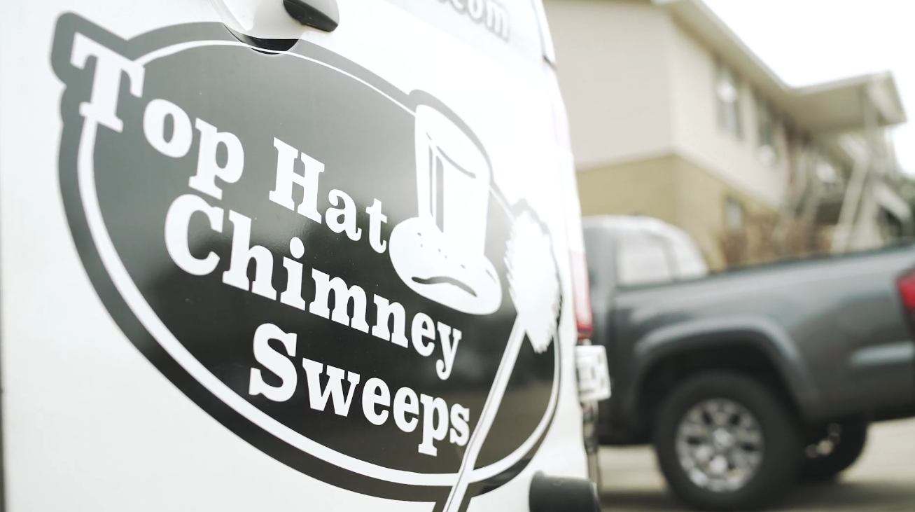 a top hat chimney sweeps truck is parked in front of a house .