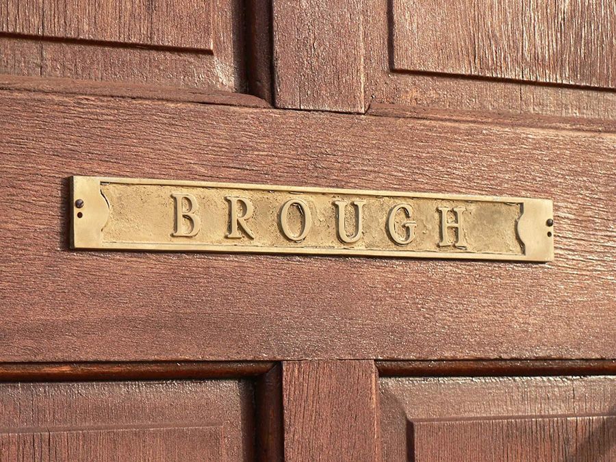 A wooden door with a brass sign that says brough