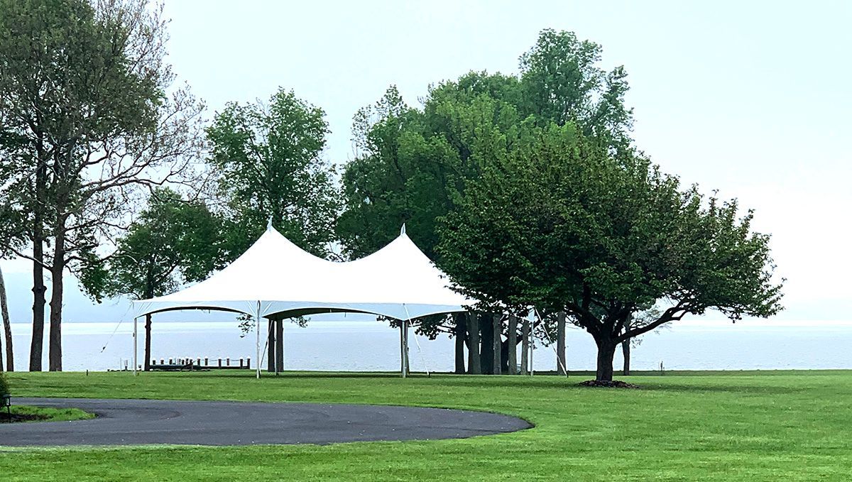 A white tent is sitting in the middle of a grassy field.