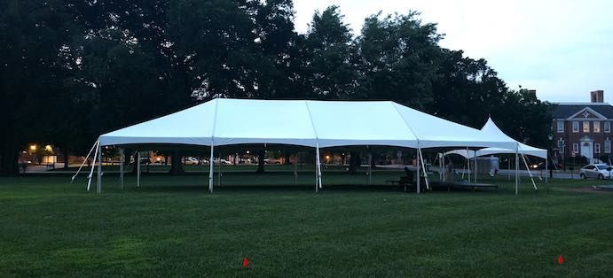 A large white tent is sitting in the middle of a grassy field.