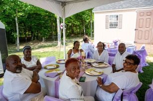 A group of people are sitting at tables under a tent.