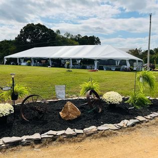 A large white tent is sitting in the middle of a grassy field.