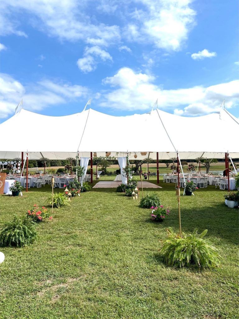 A large white tent is sitting in the middle of a grassy field.