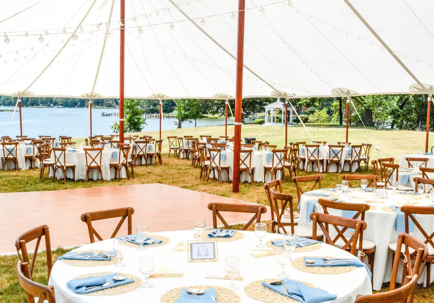 A large tent with tables and chairs set up for a wedding reception.