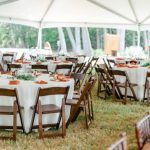 A tent with tables and chairs set up for a wedding reception.