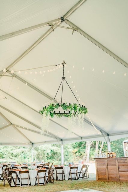 A tent with tables and chairs and a chandelier hanging from the ceiling.