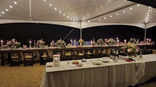A long table under a tent with candles on it.