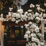A table covered in white flowers and candles.