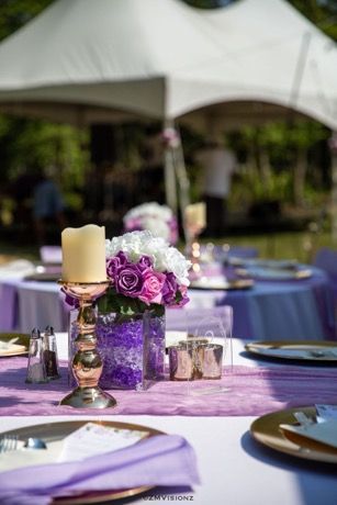 A table set for a wedding reception with purple flowers and candles