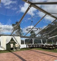 A clear tent with a brick floor and a chandelier hanging from the ceiling.