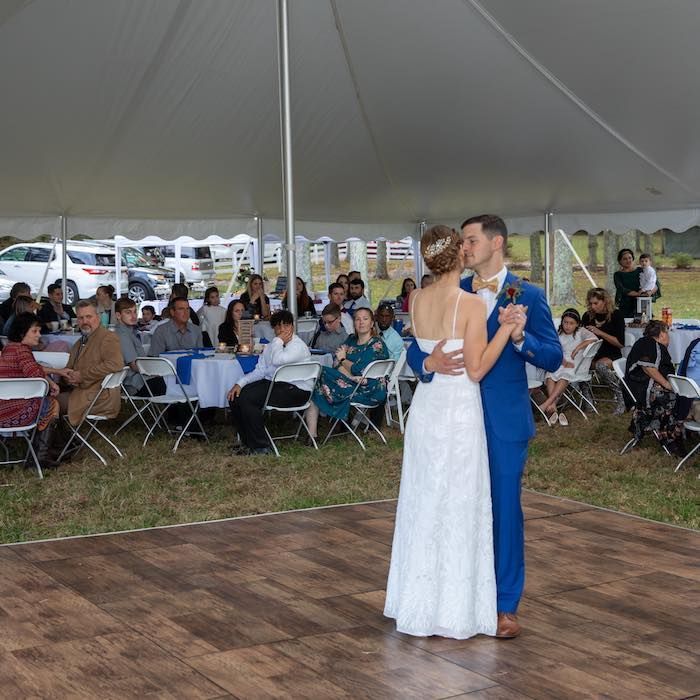 A bride and groom are dancing in front of a crowd at their wedding reception