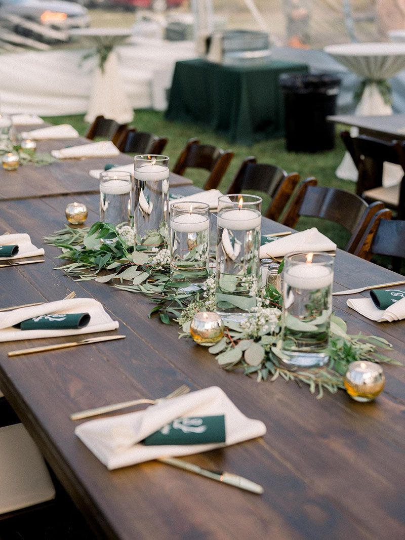 A long wooden table with candles and flowers on it.