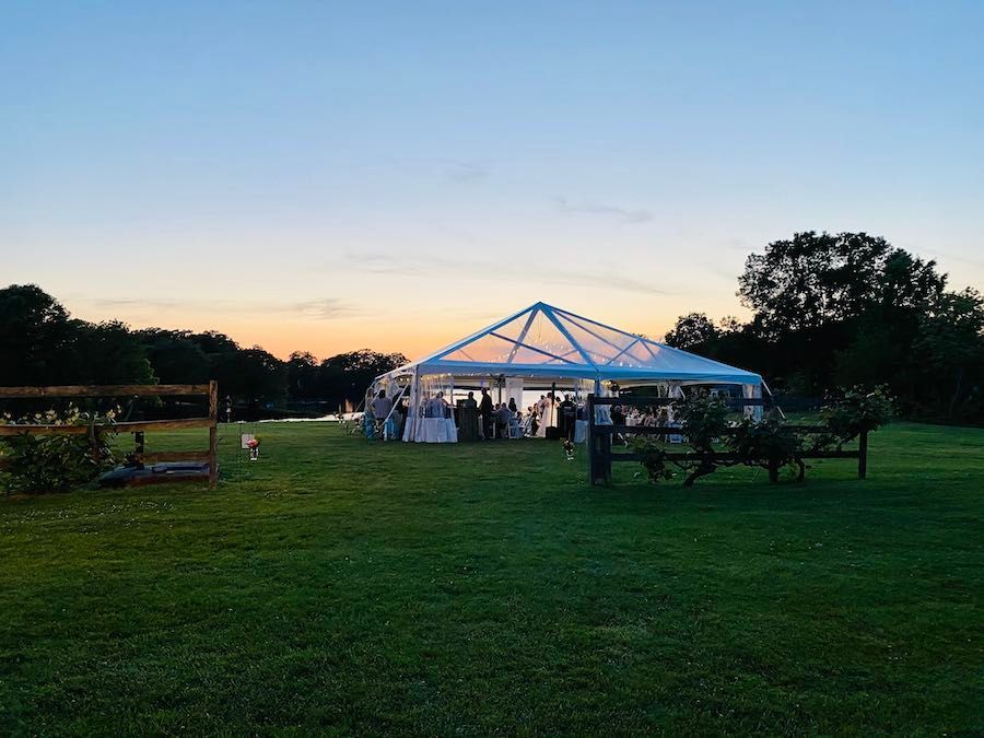 A large tent is sitting in the middle of a grassy field at sunset.