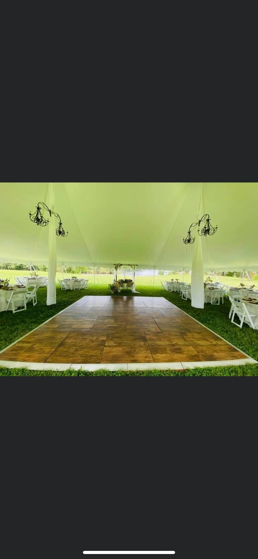 There is a wooden dance floor in the middle of a tent.