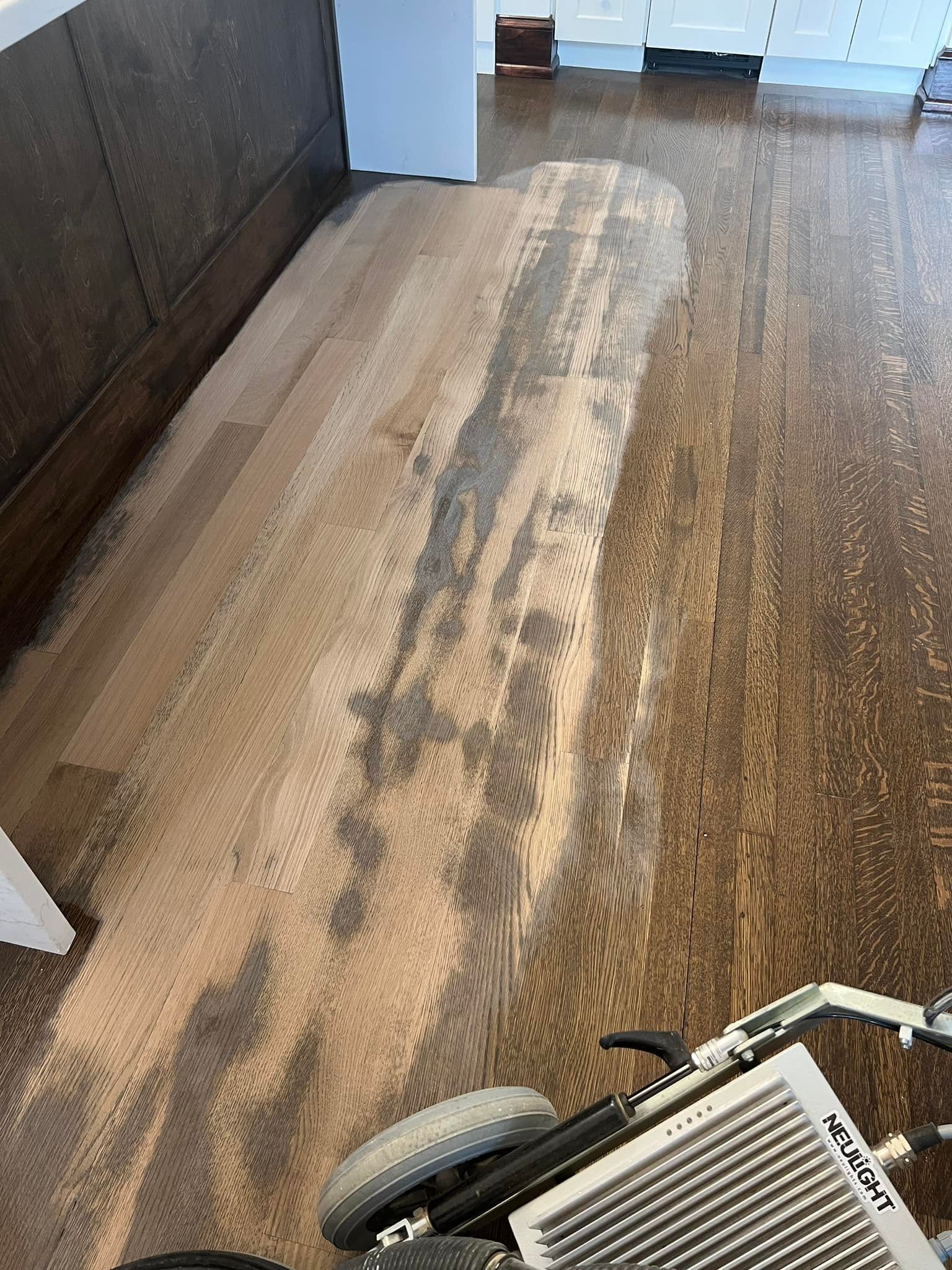 A person is cleaning a wooden floor with a machine.