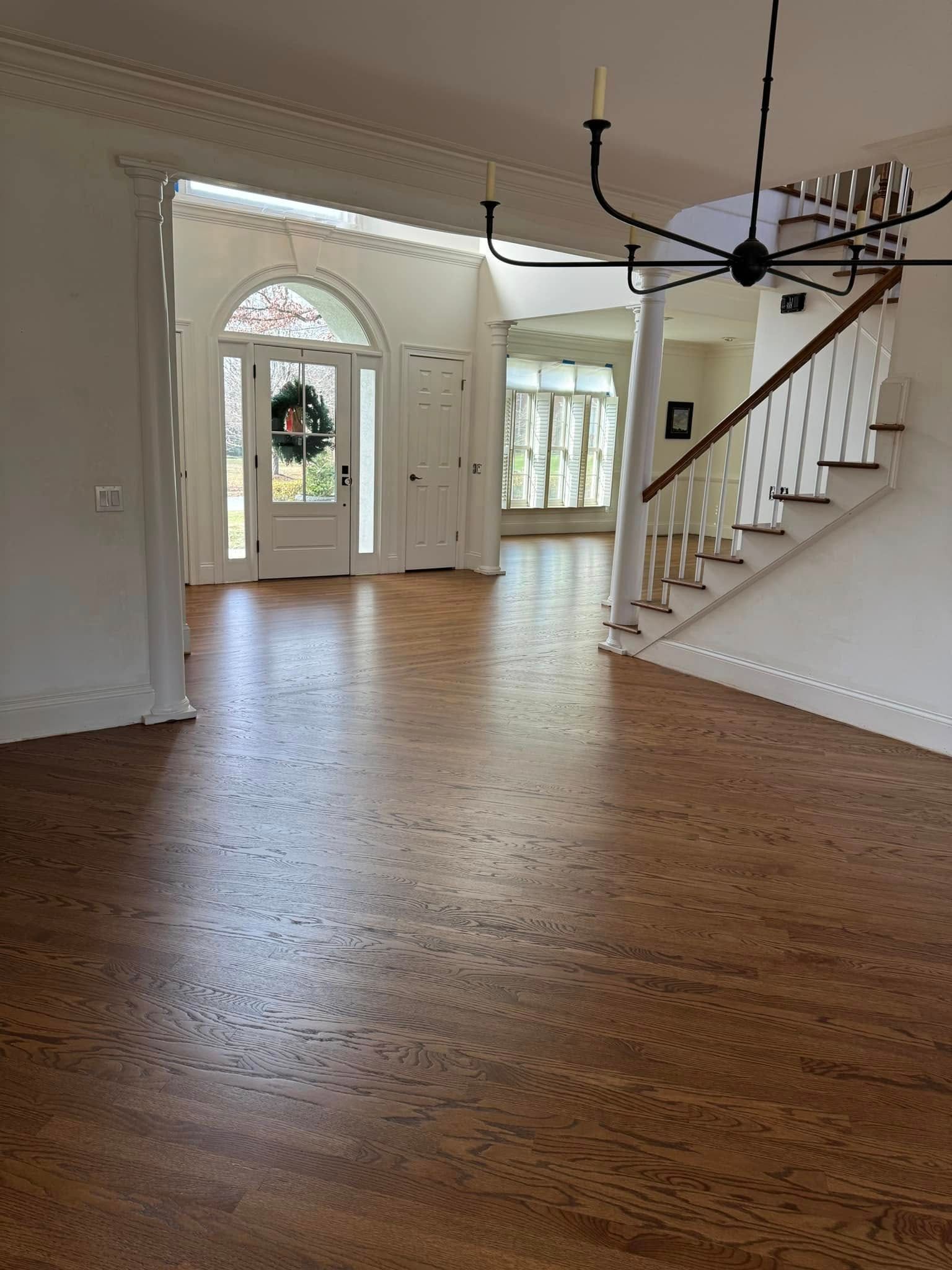 A large empty room with a wooden floor and stairs.