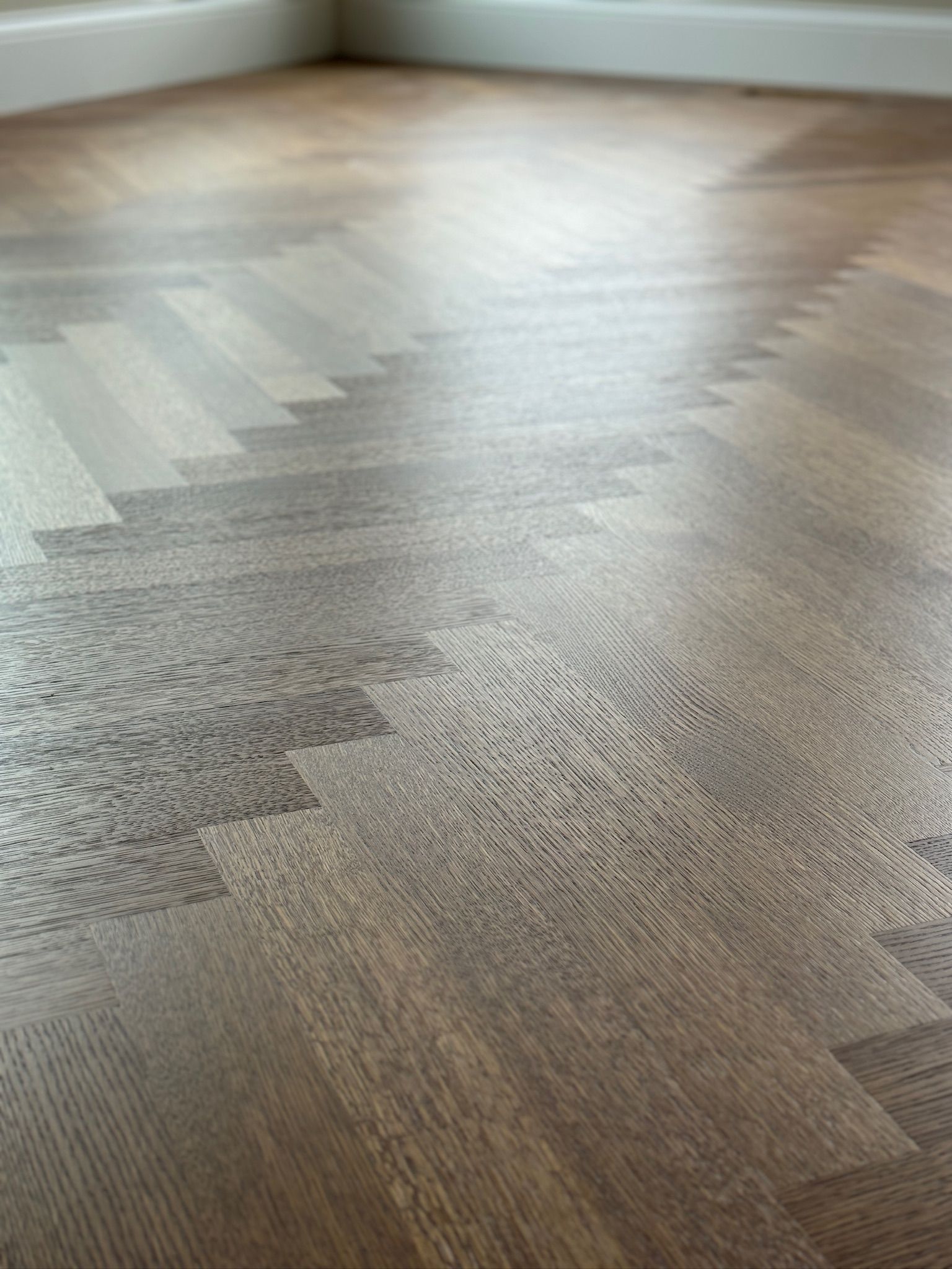 A close up of a wooden floor with a herringbone pattern.