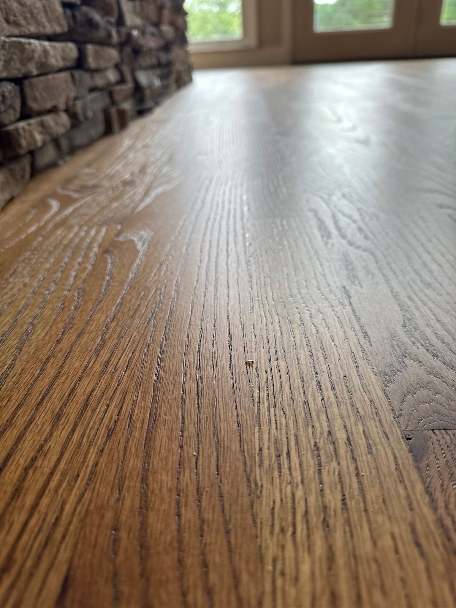 A close up of a wooden floor with a stone wall in the background.