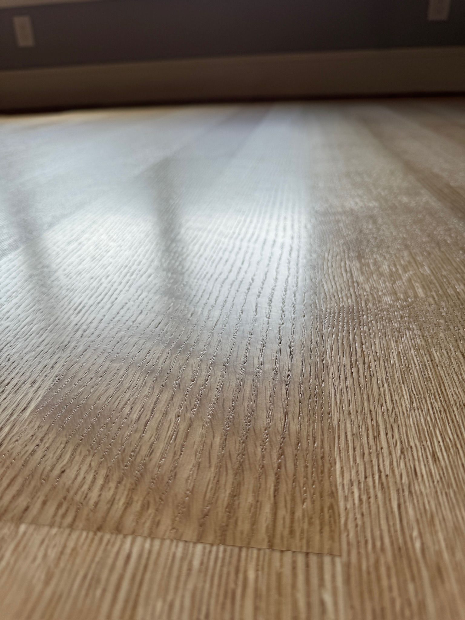 A close up of a wooden floor with a window in the background.