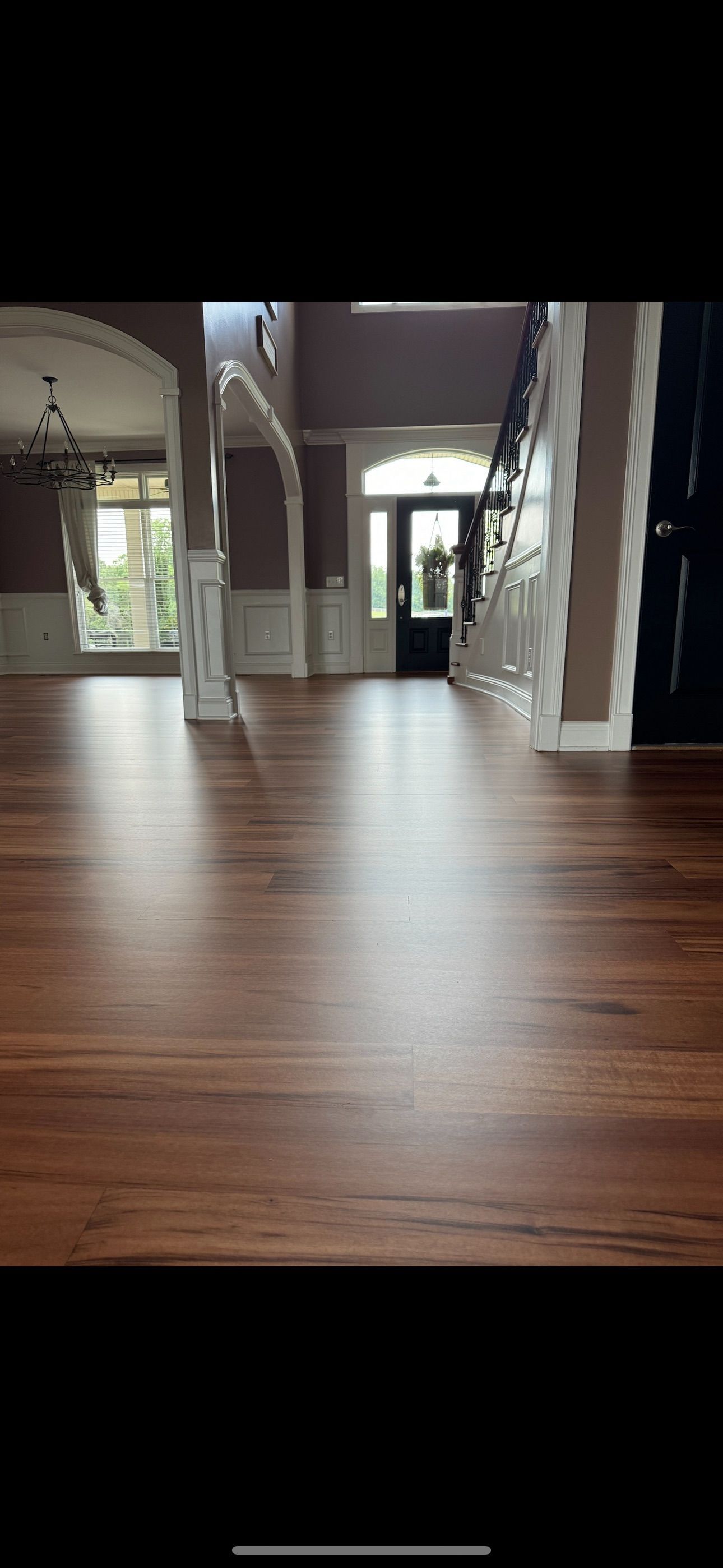 A large empty room with a wooden floor and stairs.