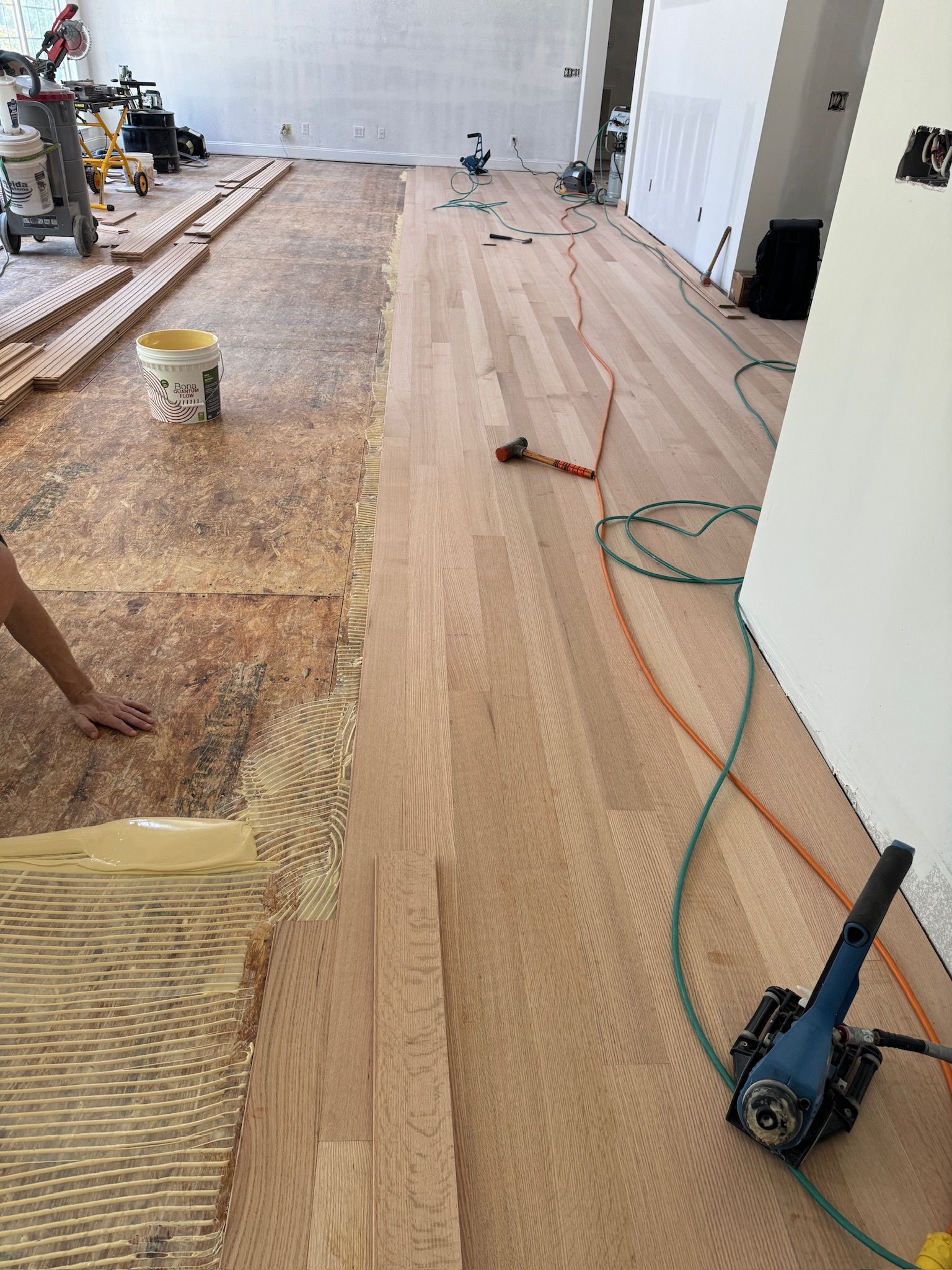 A person is working on a wooden floor in a room.