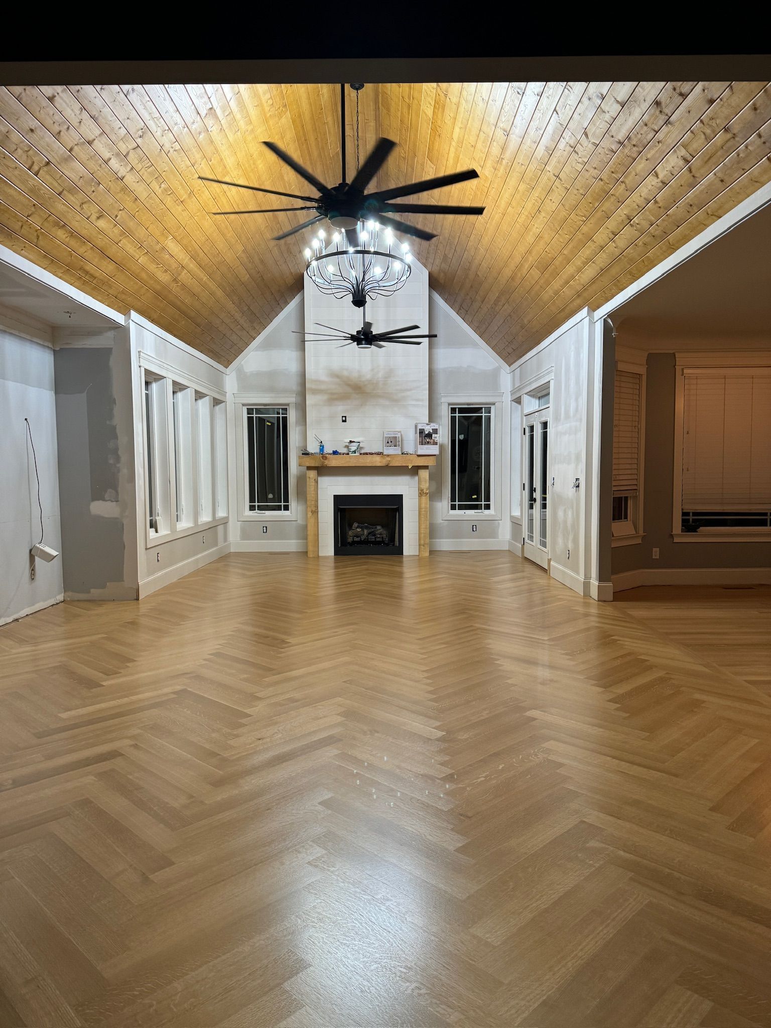 A large empty room with a fireplace and ceiling fan.