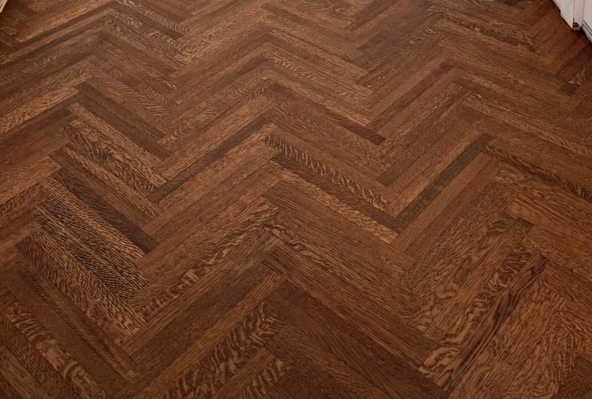 A close up of a wooden floor with a herringbone pattern.
