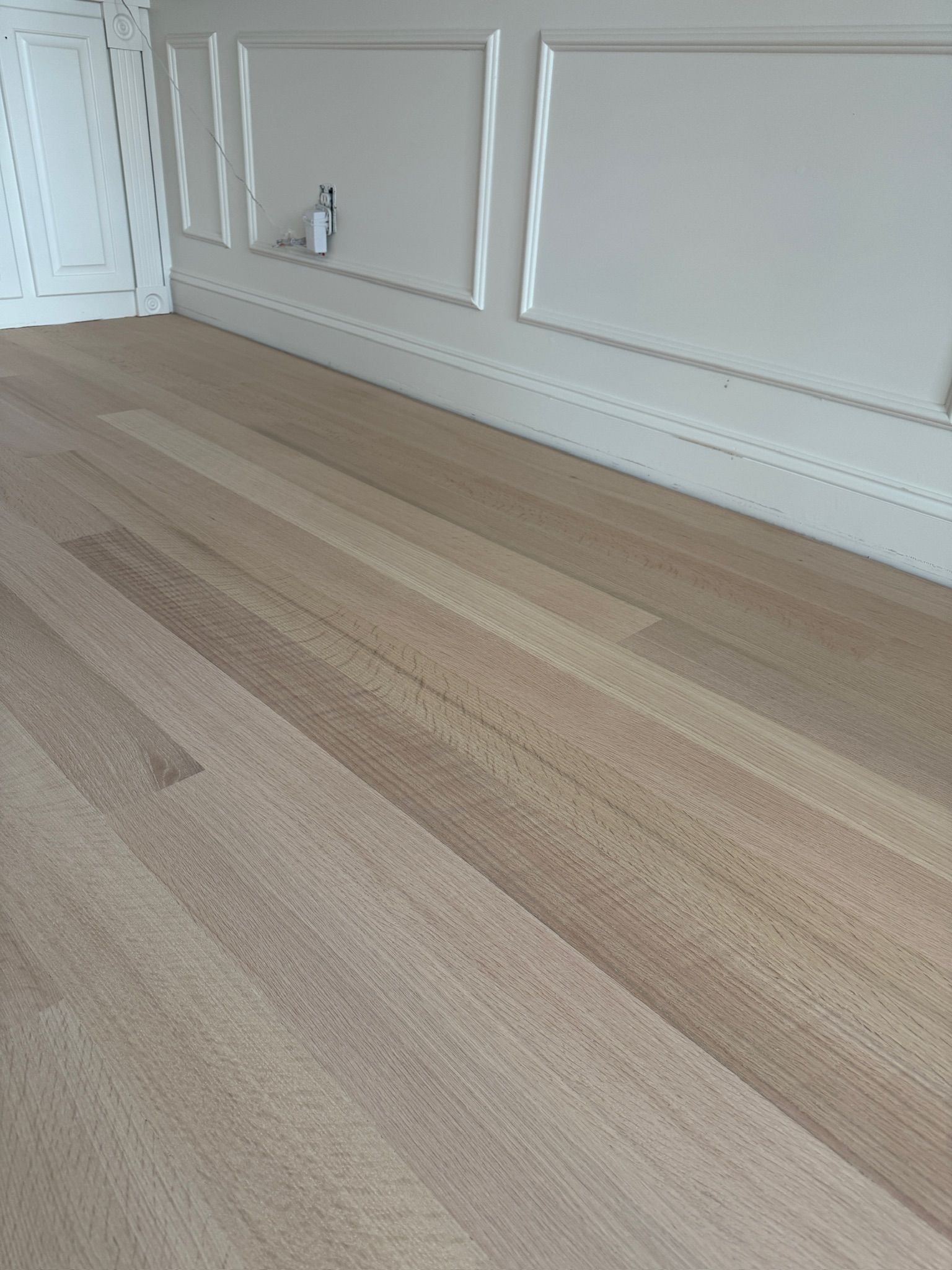 A room with a wooden floor and a white wall.