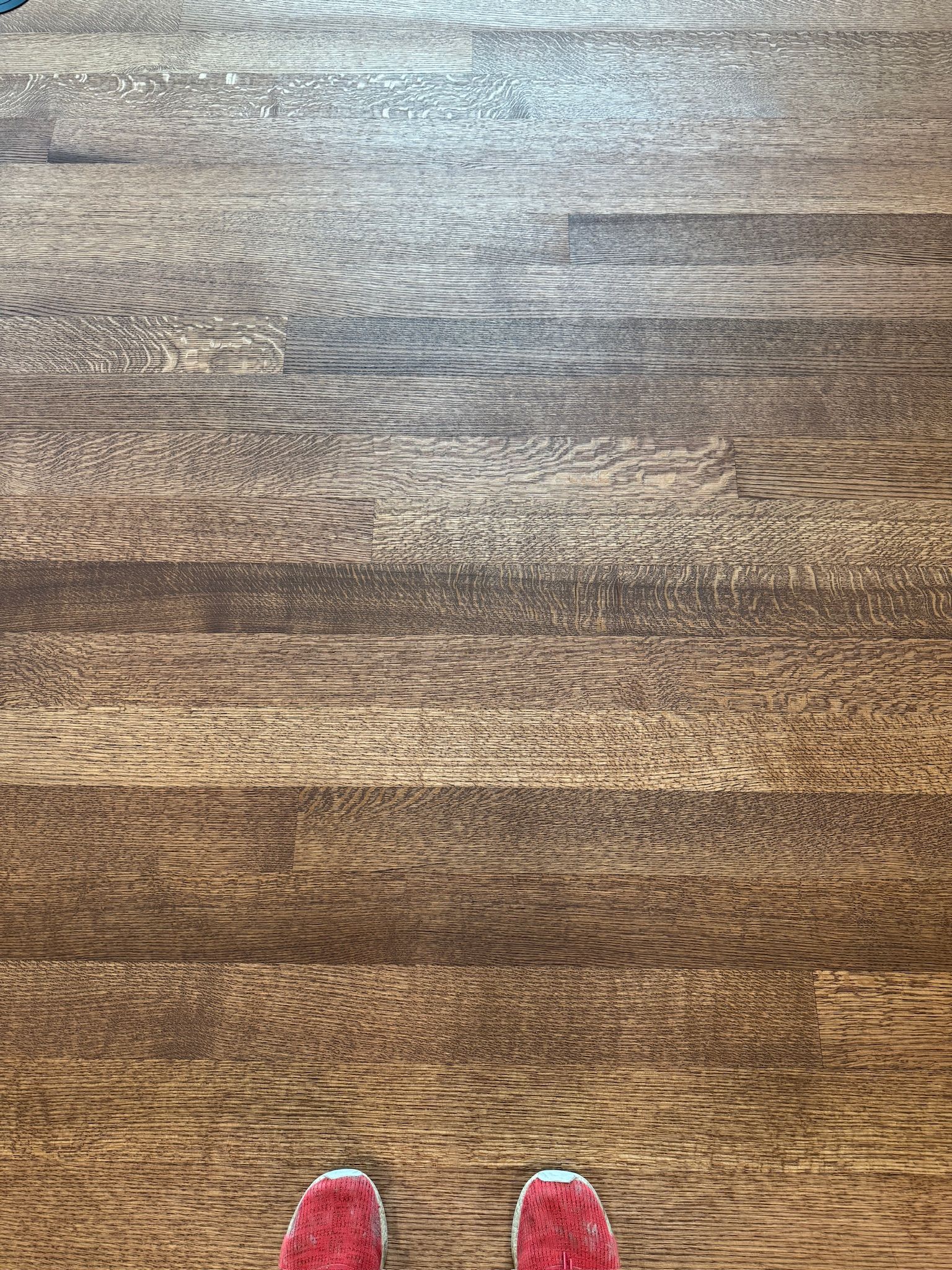 A person wearing red shoes is standing on a wooden floor.