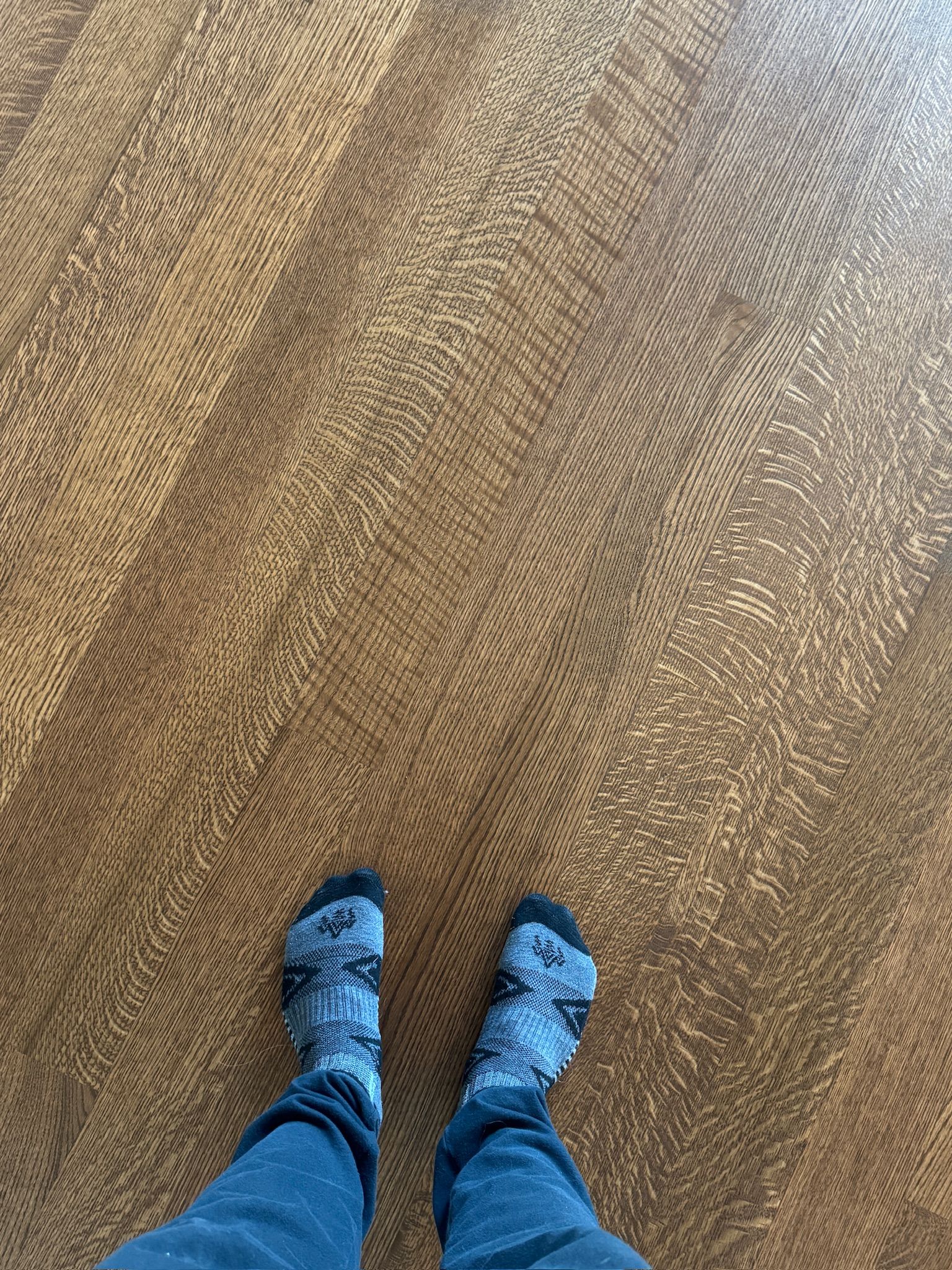 A person wearing socks is standing on a wooden floor.