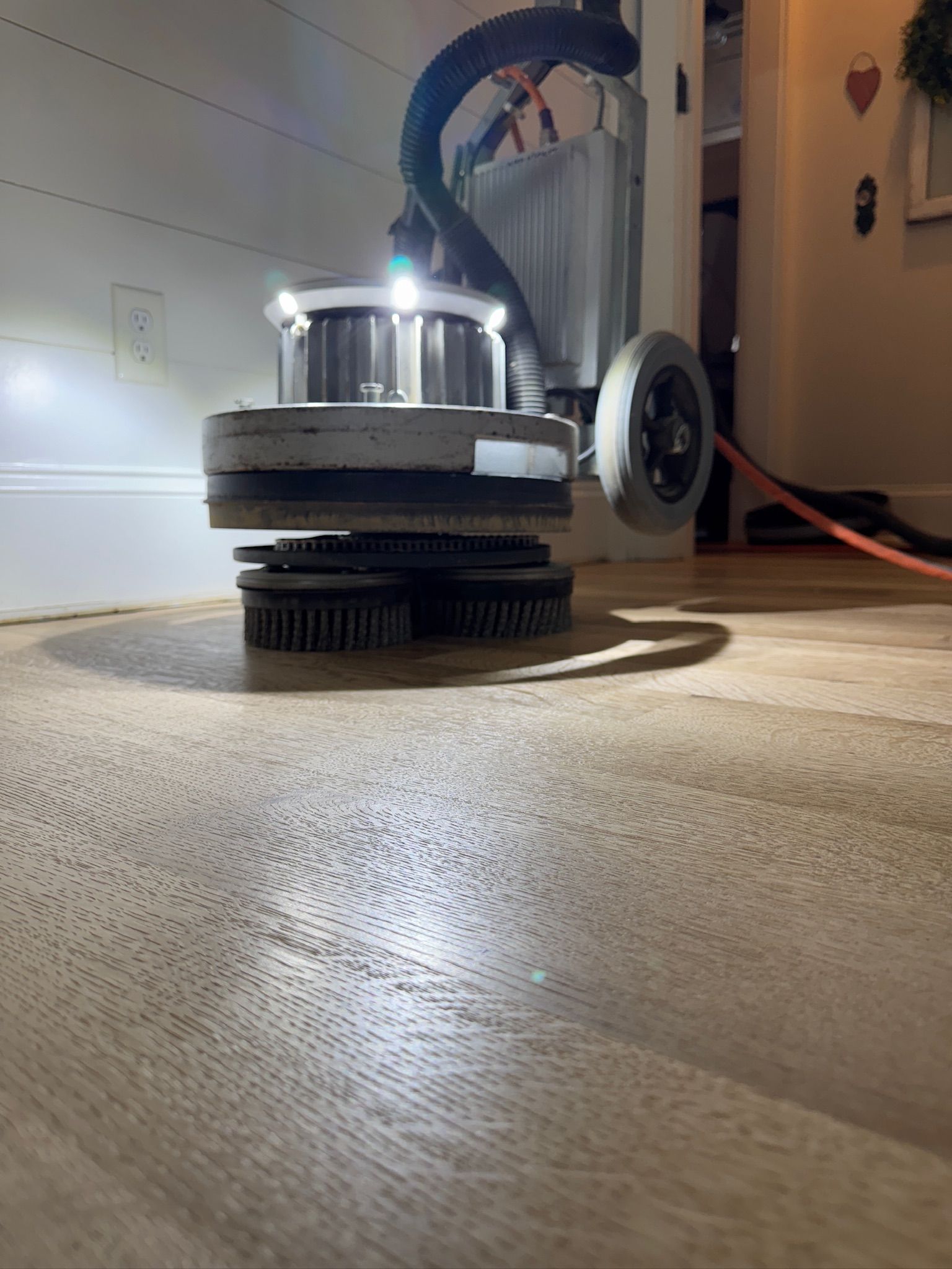 A machine is polishing a wooden floor in a room.
